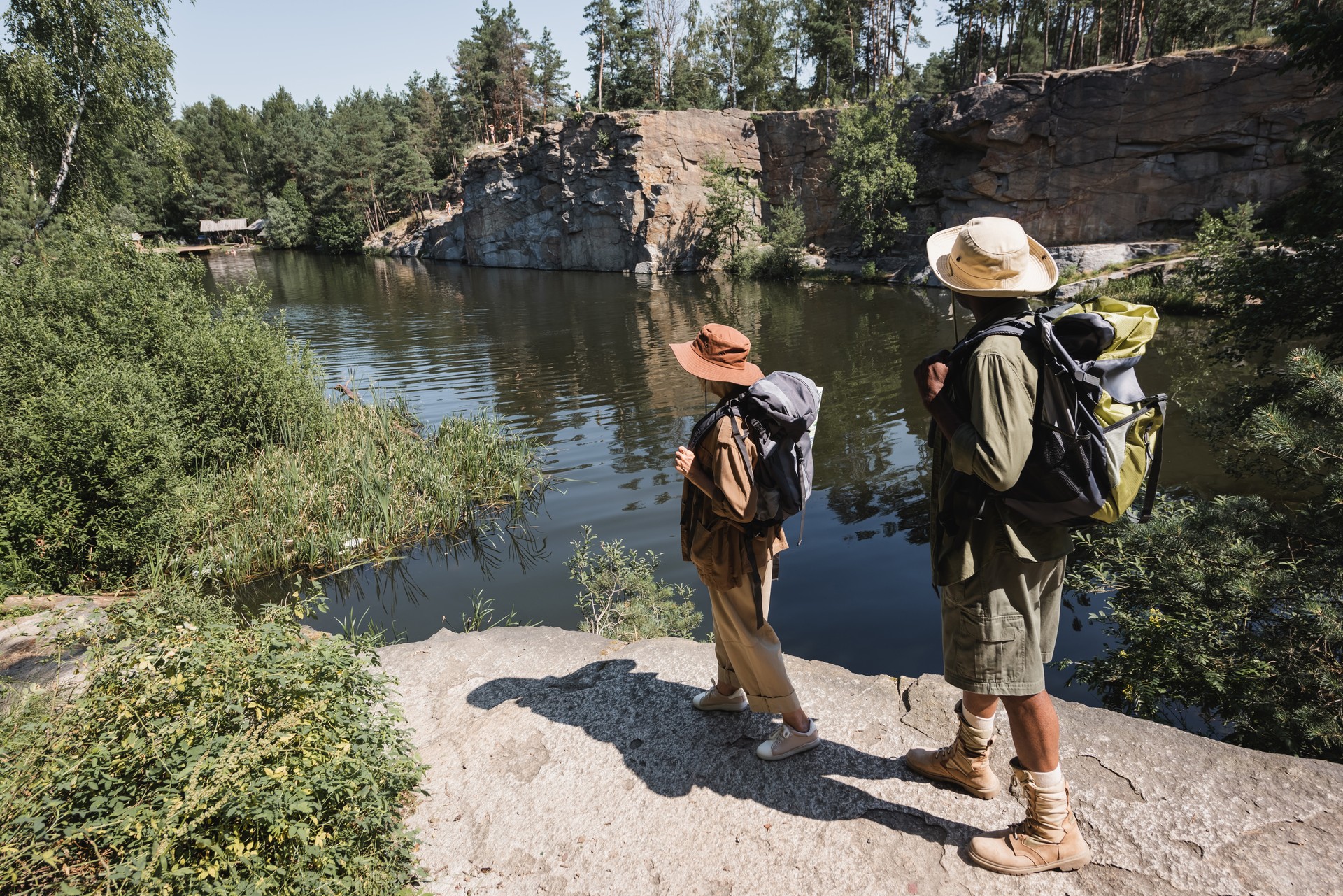 Multiethnic senior couple exploring scenic trails near a tranquil lake on a sunny day